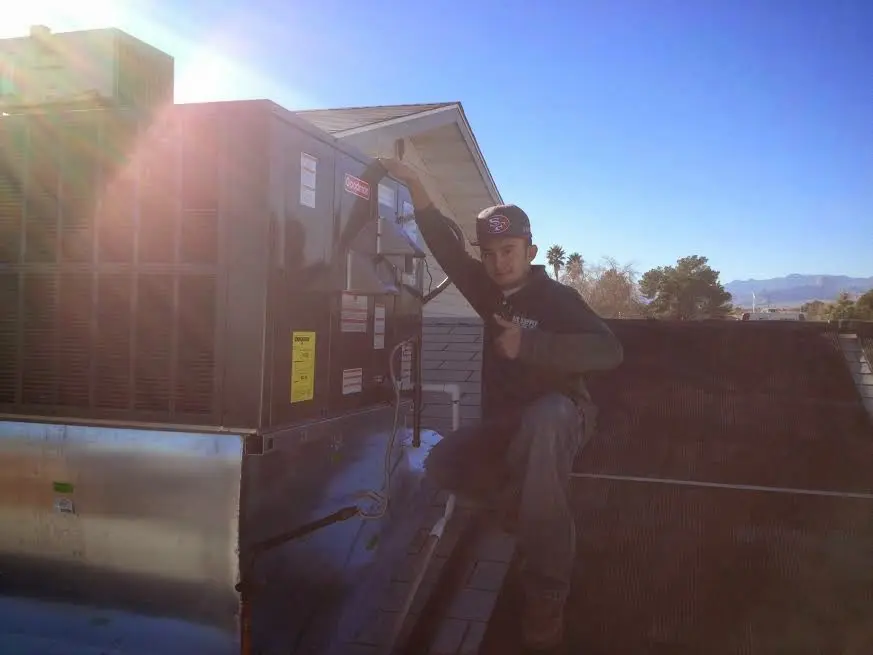 HVAC technician performing AC Tune-Up on a rooftop unit in Ridgewood village
